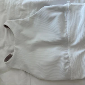 Vit ribbad linnetopp från Lululemon - Säljer en vit ribbad linnetopp från Lululemon i sportig modell. Toppen har brottarrygg och är tillverkad i ett stretchigt material som passar perfekt för träning. Snygg och enkel design med diskret logga på ryggen. Materialet är 69% nylon och 31% elastan.