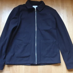 Brun overshirt från These Glory Days - Stilren brun overshirt från These Glory Days med rak passform, tre stora fickor framtill och hel dragkedja. Jackan är tillverkad i en mix av ull och polyester, vilket ger en mjuk men stadig känsla. Perfekt för lager-på-lager och enkel att matcha med det mesta. Ganska varm. Väldigt bra skick. Ungdomsstorlek L, mosvarar S.