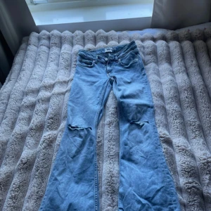 Bootcut jeans med slitna knän från 157 - Ljusblå bootcut jeans från 157 med slitna detaljer vid båda knäna. Klassisk femficksmodell med normal passform och dragkedja. Perfekta för dig som gillar en avslappnad och trendig look.