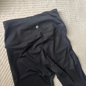 Lululemon Svarta bootcut leggings - Snygga svarta leggings Lululemon inspirerade med bootcut passform och hög midja. De är gjorda i ett mjukt och stretchigt syntetmaterial som sitter skönt och följer kroppen. Förlåt för dåliga bilder det var väldigt svårt o få till en bra bild!😅