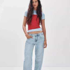 Ljusblå wide jeans från Pull&Bear - Ljusblå jeans från Pull&Bear i klassisk denim med låg midja och raka ben. Modellen har fyra fickor, gylf med dragkedja och knapp samt snyggt läderpatch bak i midjan. Perfekta för en avslappnad och trendig look, samt för nu i sommar! Och är villig att diskutera pris