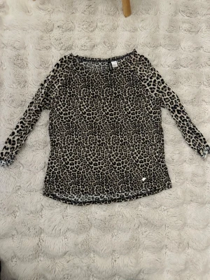 Leopardmönstrad långärmad topp H&M - Säljer en snygg långärmad topp från H&M Divided i leopardmönster. Toppen är i mjuk och stretchig polyester med beige botten och svarta/bruna fläckar. Perfekt att styla med jeans eller kjol för en cool look.