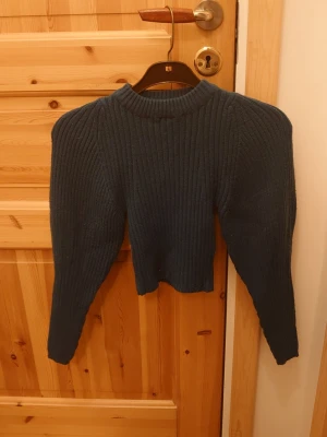 Mörkgrön stickad tröja - Mysig mörkgrön stickad tröja med ribbad struktur och lång ärm. Tröjan har en högre rundad halsringning och en något croppad passform som ger en modern look. Perfekt för kyliga dagar och enkel att styla med jeans eller kjol.☺️💕