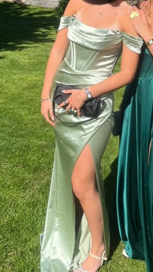 Balklänning dressroom Linné  - Snygg ljusgrön långklänning i glansigt satinliknande material. Offshoulder-modell med draperad överdel och markerad midja. Hög slits framtill för extra statement. Perfekt till bal eller student. Säljer min balklänning som endast är använd en gång den har ingen defekt och är köpt på dressroom i Göteborg. Inte fast pris vid snabb affär❤️