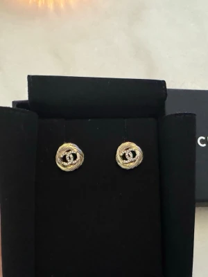 CC-örhängen i champagnefärg med kristaller - Vackra CC-örhängen med klassisk CC-logotyp i champagneton, dekorerade med glittrande strass.  Levereras med original svart -ask och påse.  Perfekta för dig som vill addera en lyxig detalj till din outfit.