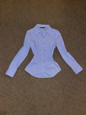 Blårandig skjorta från Zara - Tidslös figurnära skjorta från Zara, vit och blårandig. Ny utan prislapp