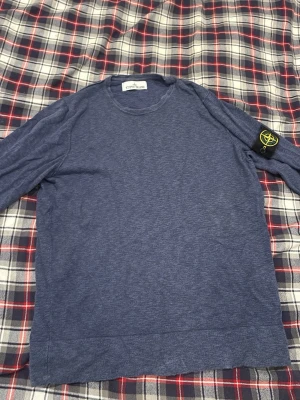  Stone Island Tröja - Säljer en mörkblå långärmad tröja från Stone Island med den klassiska loggan på ärmen. Tröjan har rund hals och är gjord i vanlig tröj material. Tröjan har inte används på ett ganska långt tag och passar M kanske S, lite slitage i halsen men annars väldigt fin