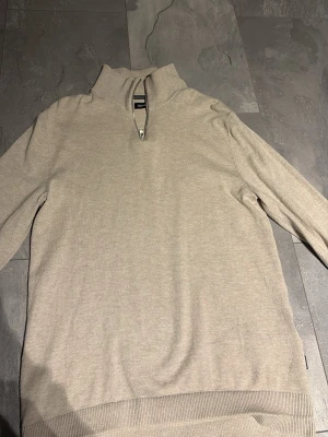 Beige half zip tröja Jack & Jones - Säljer en beige långärmad tröja från Jack & Jones med half zip-dragkedja i halsen. Tröjan har en hög krage och är gjord i mjukt material som känns skönt mot huden. Perfekt för lager på lager under höst och vinter och sommar.