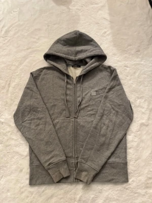 Acne ferris zip hoodie  - Skick: mycket bra, inga fläckar / hål Detaljer: 	•	Färg: grå 	•	Material: bomull 	•	Passform: regular fit 	•	storlek: S (Passar medium)  Plagget kommer från rök- och djurfritt hem.  📦 Frakt: skickas samma dag om köp går igenom innan 18.00 💬 Frågor: Hör av dig om du vill ha fler bilder eller mått 🤝 Paketpris: Samfraktar gärna vid flera köp 