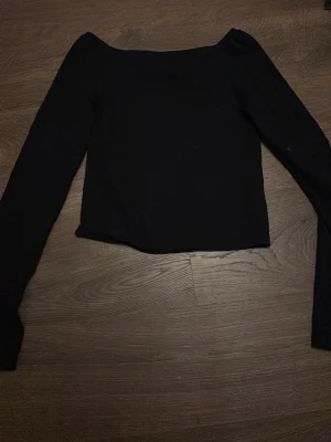 Svart långärmad topp från Kappahl - En svart långärmad topp från Kappahl i storlek 146/152. Toppen har en enkel, stilren design med rak passform. 