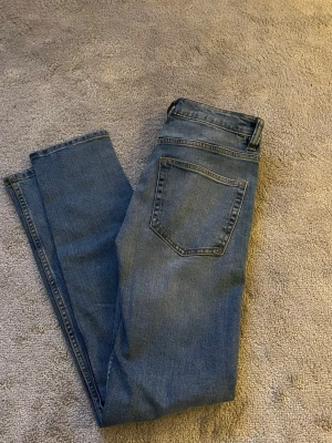 Blå slim jeans  - Säljer ett par klassiska blå jeans från lager 157 i rak modell. Jeansen har fem fickor, normal passform och snygga kontrastsömmar. Jeansen är slim fit med små slitningar som gör de unika. Perfekta till vardagslooken och funkar året runt. Materialet är slitstarkt denim i bomull. 