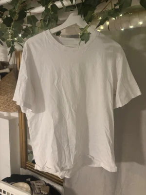 Vit t-shirt från Jack & Jones - Klassisk vit t-shirt från Jack & Jones Essentials i storlek L. Tillverkad av ekologisk bomull för en mjuk och skön känsla. Enkel design med rund hals och korta ärmar, perfekt till alla outfits.