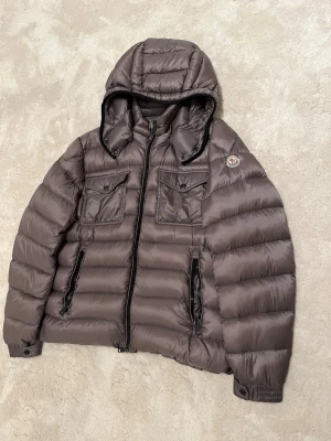 Moncler Edward Giubbotto  - Storlek:5 = XL.     dragkedjan på vänster fickan fungerar inte annars är jackan i mycket fint skick   Färg: beige aktig