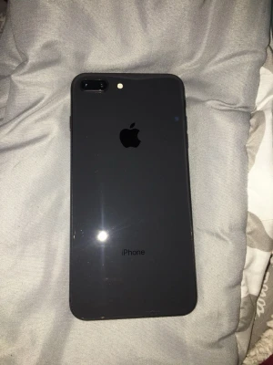 iPhone 7 Plus - Snygg svart iPhone 7 Plus med dubbla bakre kameror. Telefonen har sprickor i övre delen av skärmen men baksidan är i fint skick. Perfekt för dig som vill ha en prisvärd iPhone med stor skärm och bra kamera, men kan tänka dig att byta glaset Men funkar som en helt ny.