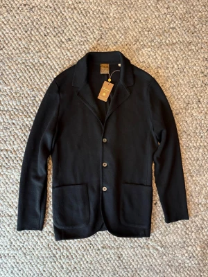 Stenströms Blazer - Stilren svart kavaj från Stenströms i mjuk merinoull. Klassisk modell med tre knappar framtill, två stora fickor och snygg krage. Perfekt för dig som vill ha en clean och tidlös look med premiumkänsla. 3,999kr ny pris 