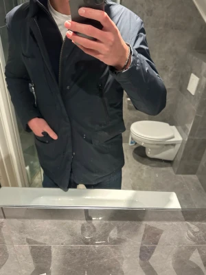 Mörkblå vinterjacka - Säljer en riktigt schysst mörkblå vinterjacka. Jackan är varm och passar perfekt nu på vintern. Jackan är i riktigt bra skick utan några defekter. Jag på bilden är 188cm lång och bär storlek M. Hör av er vid andra frågor;)