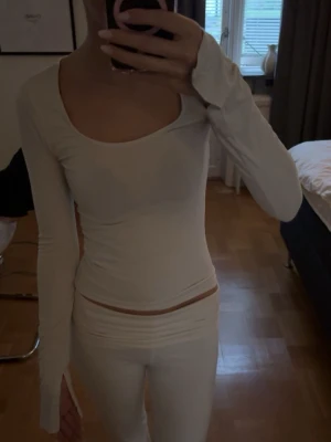 Vit långärmad topp med slits - vit långärmad topp med rundad, djup ringning och slits vid ärmsluten.