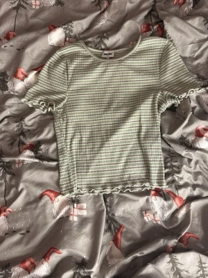 Grönvit randig topp från Bubbleroom - Säljer en söt grön och vit randig topp från Bubbleroom i storlek S. Toppen har korta ärmar med volangkant och ribbad struktur. Den är figurnära och har även volangdetaljer längst ner. Perfekt till jeans eller kjol!Helt oanvänd🩷