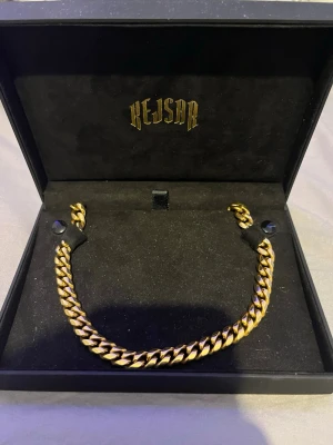 Guldfärgad Kejsar kedja - Säljer en chunky guldfärgad kedja som är guldpläterad från Kejsar. Kedjan har klassisk cuban-länk och ett stilrent lås med Kejsar-loggan ingraverad. Perfekt accessoar för att lyfta din outfit med en fet detalj. Använd ett fåtal gånger. Kedjan är ungefär 55cm lång.