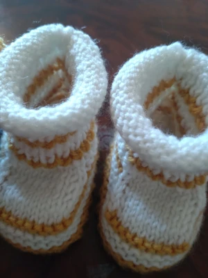 Ny handstickade babytofflor i ull - Unika handstickade babytofflor. Färgerna är vitt, gult och blått, vissa med randigt mönster och en med dekorativ blomdetalj. Perfekta för att hålla små fötter varma och mysiga under kyliga dagar.