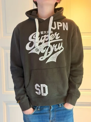 Superdry hoodie  - Bra skick, inga defekter. Vid frågor eller något så är det bara att höra av er! Moddelen är 185 och väger 75