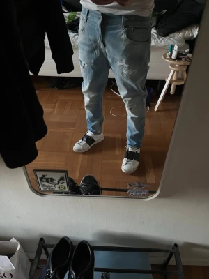 Ljusblå Dondup med slitningar - Feta Dondups med slitningar och färgstänk! W34 fits W32 och 93 cm i längd. Modellen är 178 cm lång. Superskinny sitter mer som slim fit men kan nog krympa i tvätten. Skriv vid frågor!