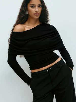 Svart offshoulder topp med cape - Säljer en svart offshoulder topp med långa ärmar och snygga rynkade detaljer över hela överdelen. Toppen är croppad och har en tight passform som framhäver axlarna. Perfekt för dig som gillar en stilren och trendig look.