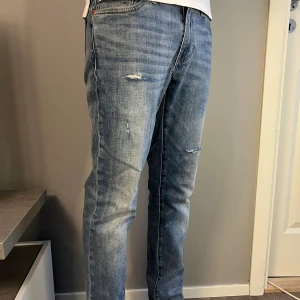 Levi’s Jeans – Ljusblå - Ljusblå Levi’s jeans i slim/regular passform med snygga slitningar och ett hål framtill för en vintage look. Storlek: Etikett saknas, men passar ca 29/32 | Skick: Mycket bra –  i övrigt hela och fräscha | Modell: Troligen Levi’s 511 