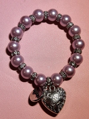 Armband - Armband med lila pärlor, en silvrig hjärtberlock samt en silvrig berlock där det står ”Isadora”. Använd men fortfarande i bra skick. Det enda som ser ”använt” ut är den silvriga berlocken där det kan synas lite repor beroende på ljuset💜