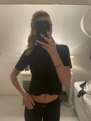 Svart croppad topp med kort ärm - Säljer en svart croppad topp med korta ärmar och låg hals. Enkel och stilren design som passar till många olika outfits. Perfekt för dig som gillar en minimalistisk look.