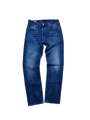 Levi's 501 blå jeans straight fit - Klassiska blå Levi's 501 jeans med rak passform och fem fickor. Jeansen har en snygg tvättad look med subtila slitningar och den ikoniska läderpatchen bak i midjan. Tillverkade i slitstarkt bomullsjeans, perfekta för en avslappnad stil.
