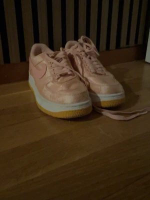 Nike Air Force 1 rosa siden - Unika Nike Air Force 1 sneakers i ljusrosa siden med broderade detaljer och matchande rosa snörning. Skorna har vit mellansula och gummifärgad yttersula. Swoosh-logga på sidan och metallbricka med 'AF1' vid snörningen. Perfekt statement-piece för dig som gillar detaljer. Säljs EJ i Sverige. Pris blev högre pga frakt 🚚 