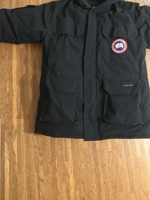 Svart Canada Goose parkas med päls - Säljer en as skön svart parkas från Canada Goose(Expedition). Tidlös design och en riktig klassiker.Jackan håller dig varm hela vintern. Det är storlek M men den är stor i storlek. Passar de större storlekarna som Large, inge defekt på jackan , köpte den ny för ett nåt år sedan på nk och har bara legat i garderoben och har använts väldigt få gånger det kommer med ett nk jack fodral, om ni har några frågor meddela gärna!😀