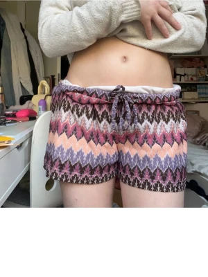 Mönstrade shorts med snörning - Säljer ett par färgglada shorts med zigzag-mönster i lila, rosa, beige och brunt. De har en relaxed passform och snörning i midjan för extra komfort. Perfekta för varma dagar och chill häng. Superfina, Strl M men passar även S, jag på bilden har vanligt S