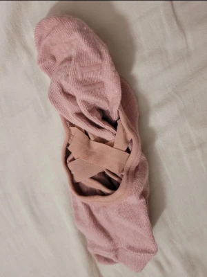 Rosa träningssockor från Crivit - Säljer ett par ljusrosa träningssockor från Crivit med halkskydd under och snygga korsade band över foten. Perfekta för yoga, pilates eller dans. Mjukt material och elastisk passform för extra komfort.