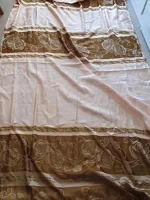 Gardin - Säljer en stor vanlig gardin i beige och brunt med vackert blommönster. Gardinens kanter har en fin fransdetalj som ger en extra touch av stil. Längd: 248 cm och Bredd: 141cm. (Det är en gardin men vet inte vilken slags men den är inte så tunn)