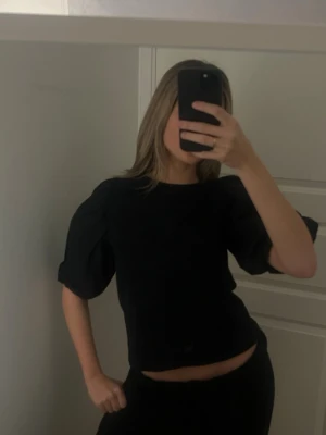 Svart puffärm blus från H&M - Säljer en svart blus från H&M i storlek XS. Toppen har puffiga korta ärmar och rak passform. Materialet känns som bomull och toppen är enkel men ändå trendig med sina markerade axlar.