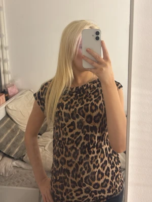 Leopardmönstrad topp från 157 - Säljer en leopardmönstrad topp från 157 i storlek M. Toppen har korta ärmar och är gjord i ett mjukt, stretchigt material som känns skönt mot huden. Färgerna går i beige, brunt och svart, tyvärr lite förstor på mig. Aldrig använd.