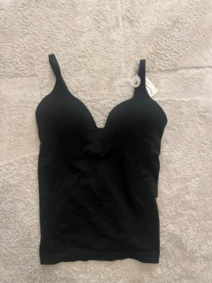 Svart topp body liknande  - Vadderad topp som liknar en body från Kappahl. Helt oanvänd med prislapp kvar, endast testad. Passar från S-L då den är stretchig
