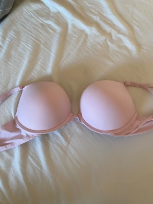 Ljusrosa bh från Victoria's Secret - Säljer en ljusrosa bh från Victoria's Secret PINK. Toppen har släta kupor, axelband som kan justeras och är tillverkad i mjukt syntetmaterial. Nästan helt ny, köpt för några veckor sedan, men passade tyvärr inte. Ena lappen är bortklippt men storleken är 70C. 