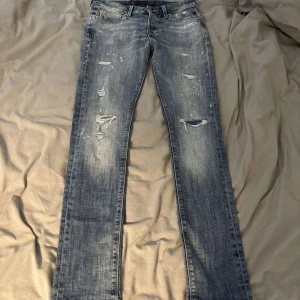 Blå slitna jeans från Jack & Jones - Säljer ett par blå jeans från Jack & Jones med slitningar och distressed detaljer både fram och bak. Jeansen har klassisk femficksdesign, raka ben och snyggt tvättad look. Perfekta för dig som gillar en avslappnad och trendig stil. Skriv om ni har frågor. Dom är typ helt nya. Storlek 29/32