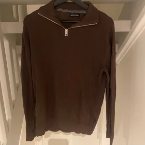 Brun half zip tröja från Jack & Jones - Snygg brun långärmad tröja från Jack & Jones med half zip-dragkedja vid kragen. Tröjan har en enkel och stilren design, perfekt för dig som gillar en clean look. Materialet känns mjukt och skönt mot huden och passformen är normal.