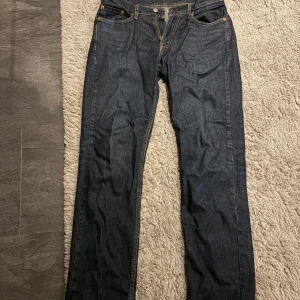 Levi's 514 mörkblå jeans W30 L32 - Snygga mörkblå Levi's 514 jeans med klassisk femficksdesign och raka ben. Jeansen har kontrastsömmar och ikonisk läderpatch bak i midjan. Perfekt passform för dig som gillar en straight look.