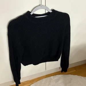 Svart stickad tröja Gina Tricot XS - Svart stickad tröja från Gina Tricot i storlek XS. Tröjan har en klassisk rund halsringning och långa ärmar. Den är ribbstickad vid halsen och muddar, vilket ger en snygg och enkel look. Perfekt att matcha med jeans eller kjol.