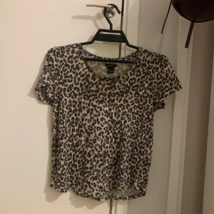 Leopardmönstrad tshirt Lindex - Säljer en kortärmad tröja från Lindex i storlek S med ett snyggt leopardmönster i beige och svart. Toppen har rund halsringning, mjukt luftigt material. Perfekt för dig som gillar djurprint och vill sticka ut lite extra.