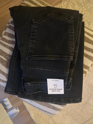 Bootcut jeans i offblack, storlek 36 - Helt nya med prislapp. Modellen heter low waist petite bootcut. Snygga bootcut jeans i offblack med låg midja och petite passform. Klassisk femficksdesign och mjukt jeanstyg som ger en skön känsla. Perfekt för dig som gillar en stilren look med lite extra edge. Storlek 36.