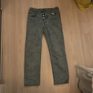 Levi's 501 ljusblå jeans W24 L26 - Säljer ett par klassiska Levi's 501 jeans i ljusblå tvätt med raka ben och knappgylf. Modellen har fem fickor och den ikoniska röda Levi's-taggen bak. Perfekt passform för dig som gillar tidlös denimstil.