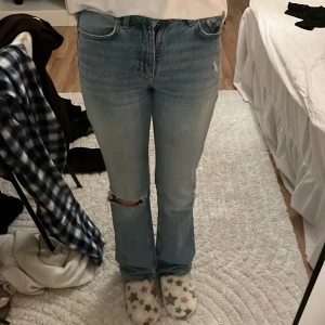 Gina tricot ljusblå jeans med bootcut stl 32 - Ljusblå jeans med klassisk femficksdesign och bootcut-ben. Jeansen har hög midja och är tillverkade i slitstarkt bomullsjeansmaterial. Snygga slitningar och hål vid knät ger en cool, avslappnad vibe. Perfekta för dig som gillar vintage och streetstyle. Två små små hål som inte syns när man har på sig dom🥰