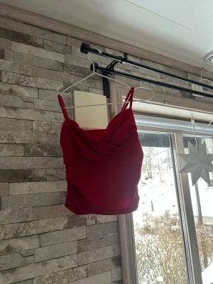 Röd croppad linne med drapering - Trendig röd croppad linne med smala axelband och snygg drapering framtill. Perfekt för att lyfta din outfit med en färgklick 