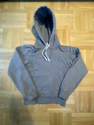 Grå hoodie från Lacoste - Snygg grå hoodie från Lacoste. Storlek Xs och passar 165 typ. Mycket bra skick och inga defekter.